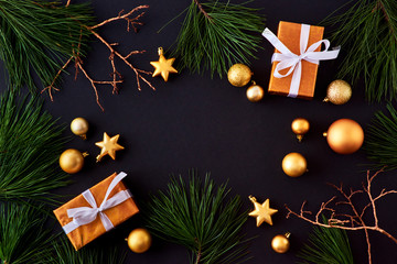 Flat lay frame with gold christmas balls, pine branches and gift box on a dark background