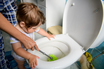 Mom teaches a child to clean. cleaning after the baby. clogged toilet. Mom and baby clean the...