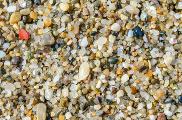 Pebble beach. Small colored sea stones close-up. Multicolor seabed. Selective focus image, copy space. Sea beach backdrop. Summer holiday concept.