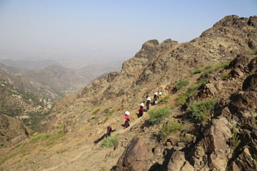Yemeni women bring their food and drink needs across rugged mountain roads due to the war and the...