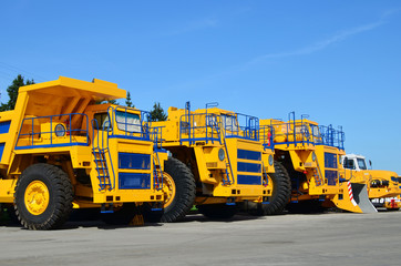 Heavy-duty trucks warehouse at autoworks. Giant mining dump trucks manufacture by the heavy vehicle plant. Heavy quarry equipment. Coal mining, granite, gravel, sand.