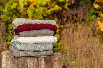 a stack of colored blankets on autumn forrest background in warm lights