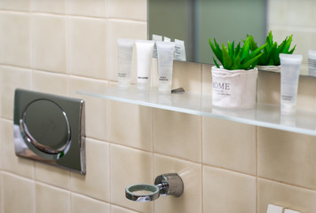 Close-up of glass shelf with cosmetics in modern bathroom interior.