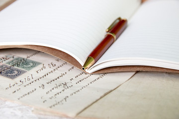 Pen on notebook in front of vintage old papers