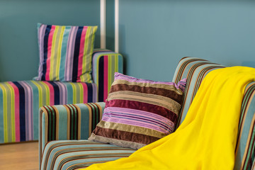 Close-up of cozy couch with pillows and yellow plaid. Stripes.