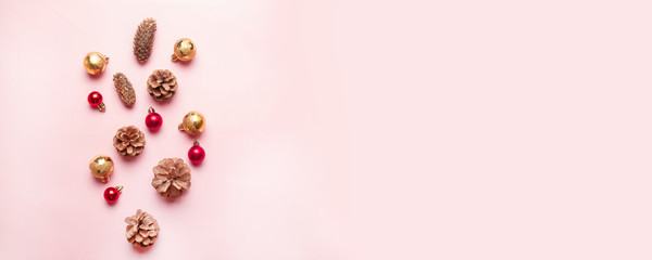 Christmas or New Year composition with pine cone, gold and red balls on a pink background.