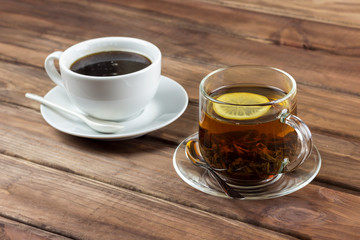 cup of tea with lemon and a cup of coffee on a wooden surface, the choice between coffee and tea