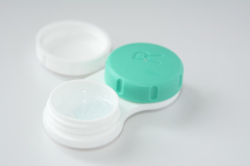 container for soft contact lenses and lens on light background