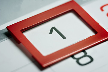 the first day of the month highlighted on the calendar with a red frame close-up macro, a mark on the calendar