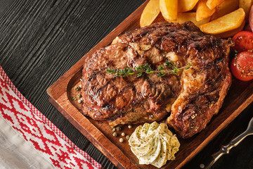 Ribeye steak with potatoes, onions and baked cherry tomatoes. Juicy steak with flavored butter