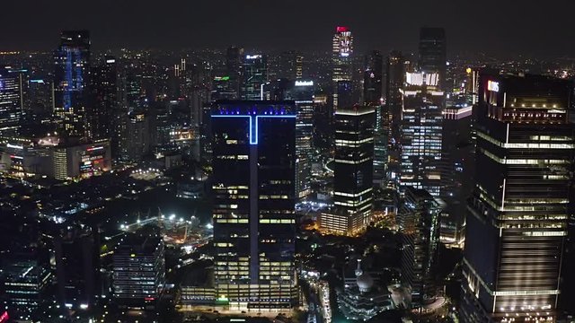 JAKARTA, Indonesia - October 03, 2019: Beautiful aerial landscape of modern office buildings with night lights in business district. Shot in 4k resolution from a drone flying forwards