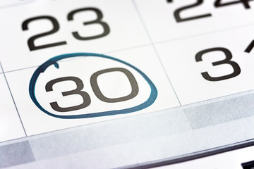 the thirtieth day of the month highlighted on the calendar close-up macro, the mark on the...