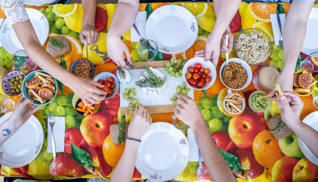 Healthy vegetarian meal on top of colorful table with friends, from above