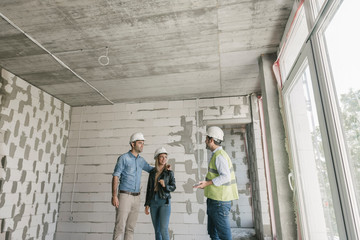 Architect talking with future owners on construction site