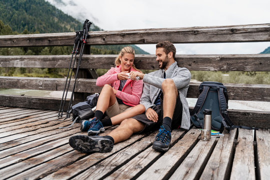 Young couple having a break on a wooden, bridge during a hiking trip, Vorderriss, Bavaria, Germany