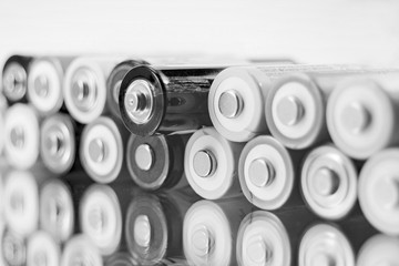 alkaline AA batteries on the glass surface with close-up reflection, salt batteries, accumulators, black and white photo
