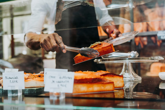 Man working in a bakery putting a piece of cake on a plate