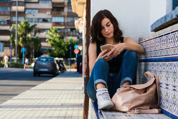 Young woman is using her smartphone on the street