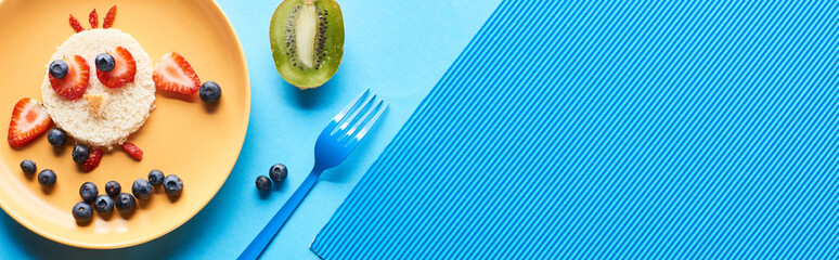 top view of plates with fancy animals made of food on blue background, panoramic shot