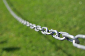 Slacking steel chain with a chain link is in focus and the rest in the blur