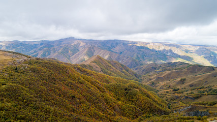 Wild mountainous place in autumn with yellow, red and green trees.