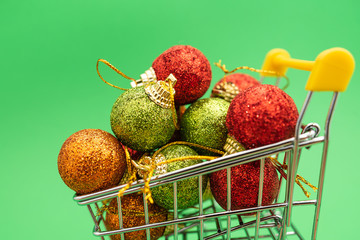 New Year's toys in supermarket trolley on green background. Christmas shopping concept