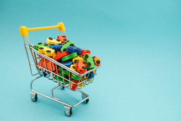 mini toy rubber cars in supermarket trolley on blue background