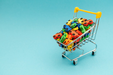 mini toy rubber cars in supermarket trolley on blue background
