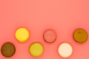 delicious macarons arranged in a row on pink background with copy space