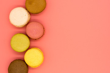 delicious macarons arranged in a row on pink background with copy space
