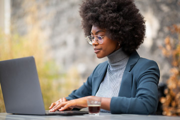 professional young black businesswoman sitting outside with laptop