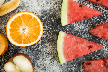 Watermelon slice on wooden cutting board summer fruit. Bananas and nictarin with apple on table. Healthy fruits.