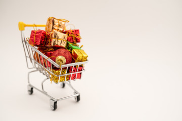 New Year's gifts and toys in supermarket trolley on white background. Christmas shopping concept