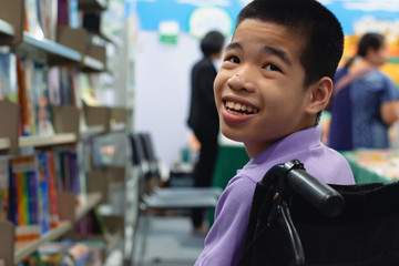 Disabled child on wheelchair trying begged parents to buy a book for him in books and toys fair,Special children lifestyle,Life in the education age of special need kids,Happy disability kid concept.