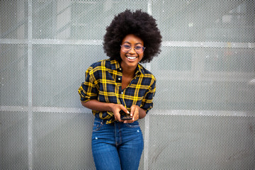 happy smiling young black woman with afro hair holding mobile phone