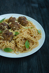 Pasta with meatballs and parsley in tomato sauce. Dark wooden background. View from above.