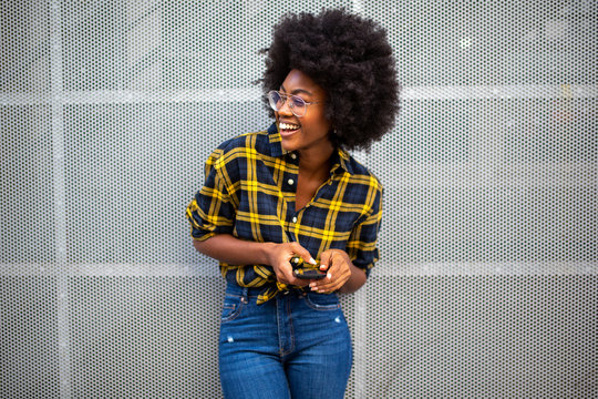 happy smiling young black woman with afro hair holding cellphone