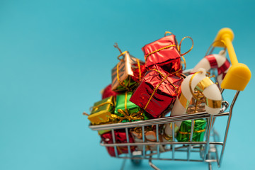 New Year's gifts and toys in supermarket trolley on blue background. Christmas shopping concept