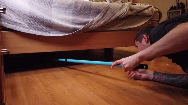 Young man washing floor at home. Closeup of a man's wiping dirt from a wooden floor with a special cloth.