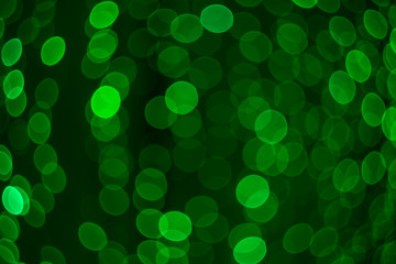 Beautiful festive colored bokeh of glowing circles of green, twisting into the shape of a sphere. Abstract composition.