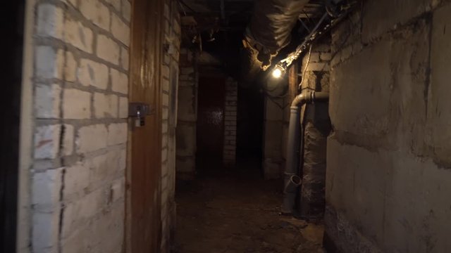 man runs through an old abandoned building, basement with lantern.