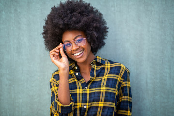 front portrait of young afro woman holding glasses and smiling against green background