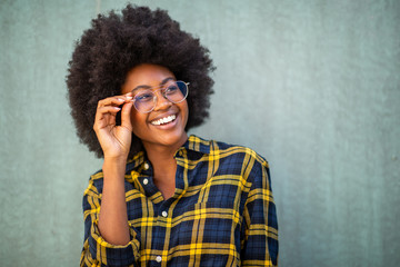 Close up young afro woman holding glasses and smiling against green background