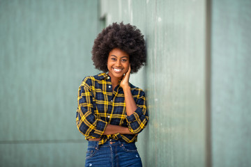 smiling young african american woman leaning against wall - Powered by Adobe