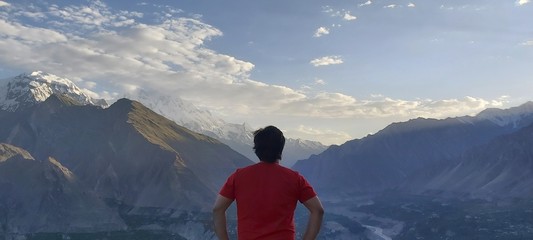 Person standing and facing back on mountain