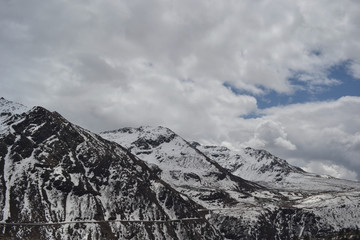 dark mountain cliffs covered in snow and cloudy sky