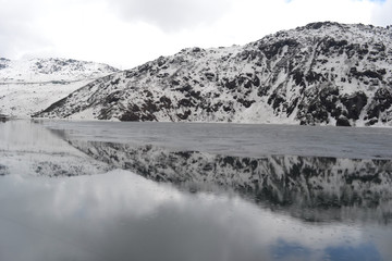 rain on snowy mountains and frozen glacier lake