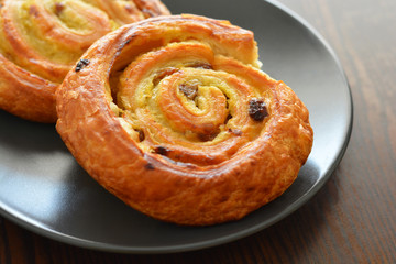 Danish raisin swirls on a black plate. French pastry.