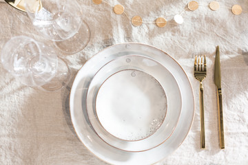 empty plate with gold fork and knife on tablecloth