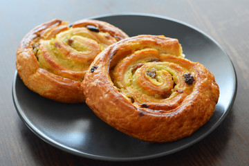 Danish raisin swirls on a black plate. French pastry.